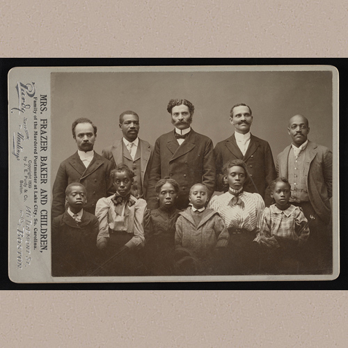 Photograph shows Lavinia Russell Baker (also spelled Levina and Levinah in historical records) and her five surviving children, with five men, after the lynching of her husband, Lake City, South Carolina, Postmaster Frazer or Frazier Baker, and their daughter, Julia, on February 22, 1898. The Post Office and Baker family home was burned and family members were attacked by gunfire as they sought to escape. | Library of Congress Prints and Photographs Division Washington, D.C. 20540 USA | Date Created/Published: Boston : [J.E. Purdy & Co.], [1899]